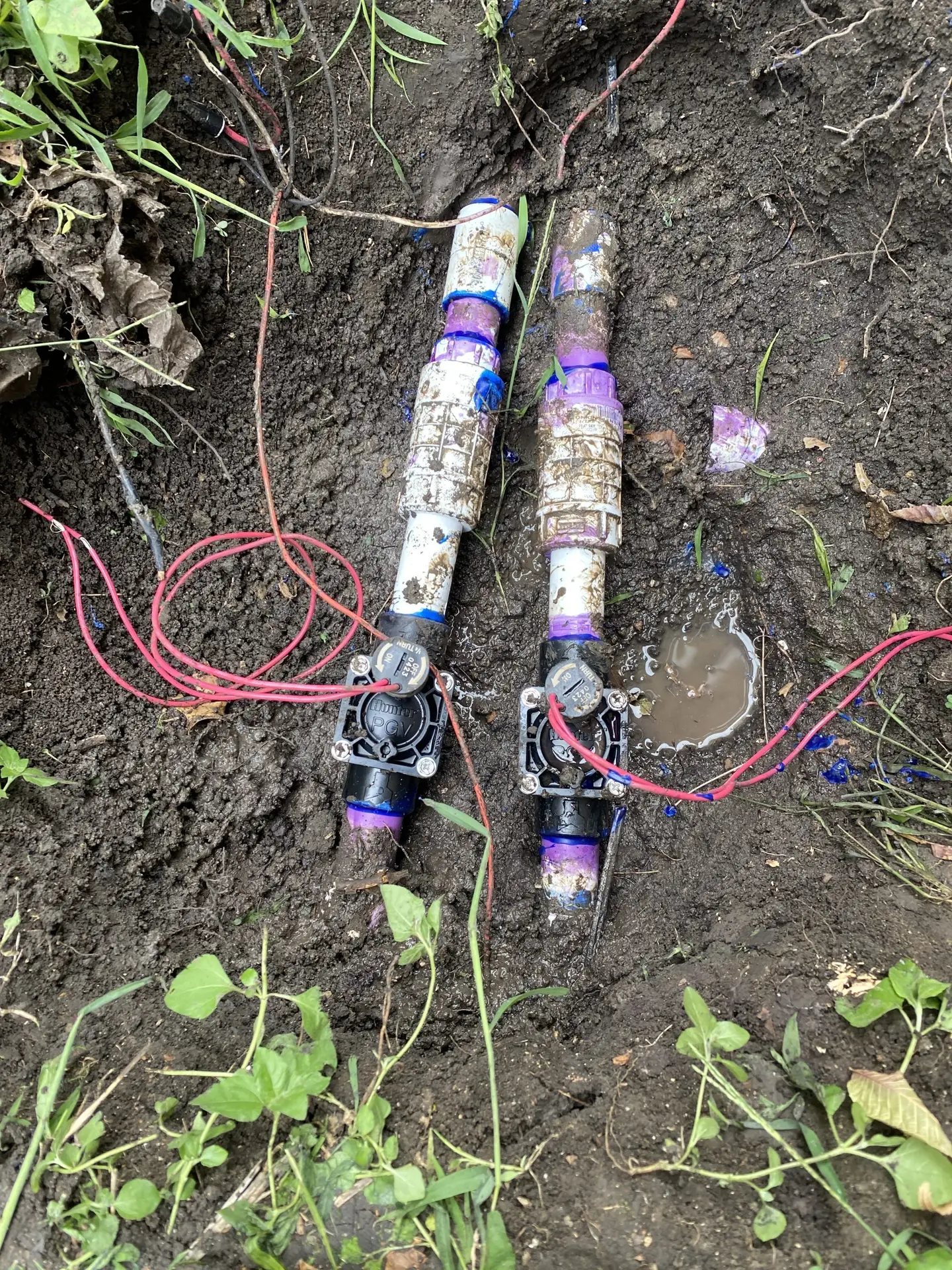 Sprinkler valves with solenoids and wiring exposed during a valve repair